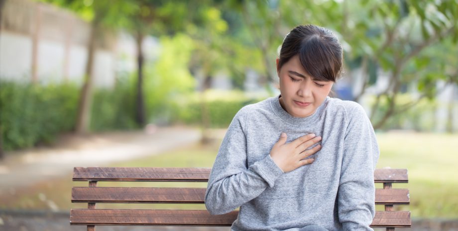 Women shows signs of acid reflux while sitting in the park