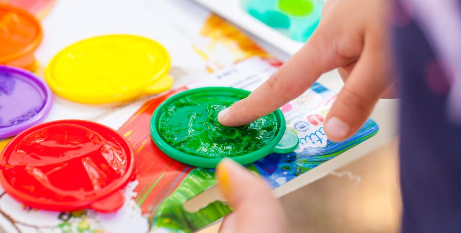 Kids painting with their fingers with color palette