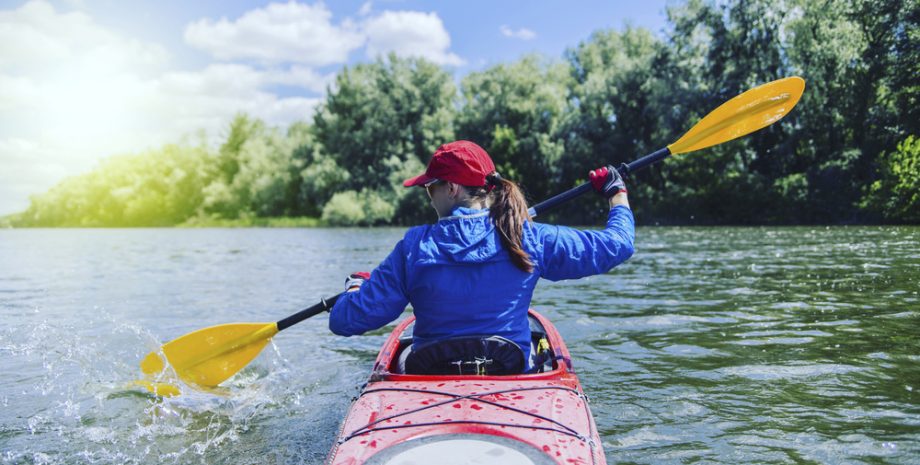 A girl rafts on a kayak on a river on a sunny day