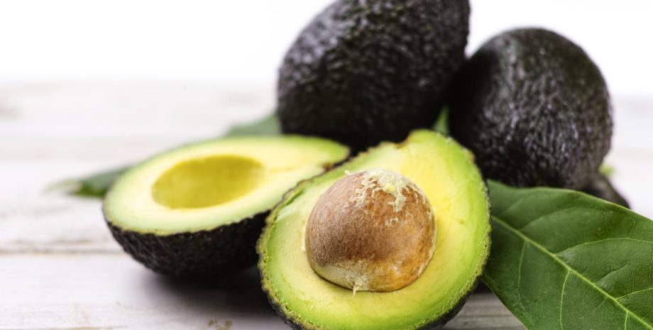 Green ripe avocado with leaves close up