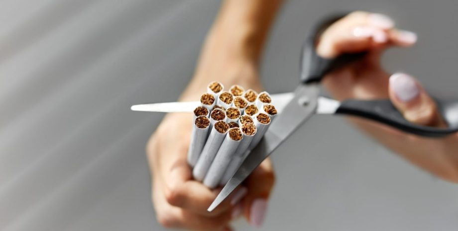 Closeup Of Female Hands Cutting Cigarettes With Scissors