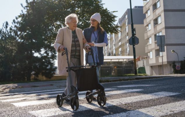 A young woman helping an elderly person across the road.