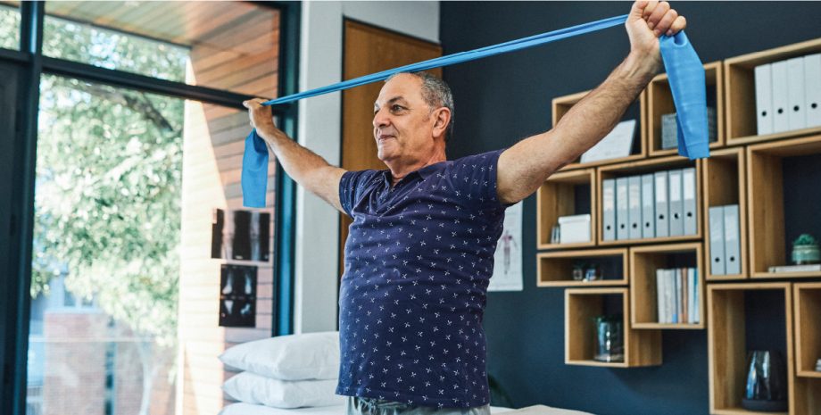 An older man using workout bands to stretch.