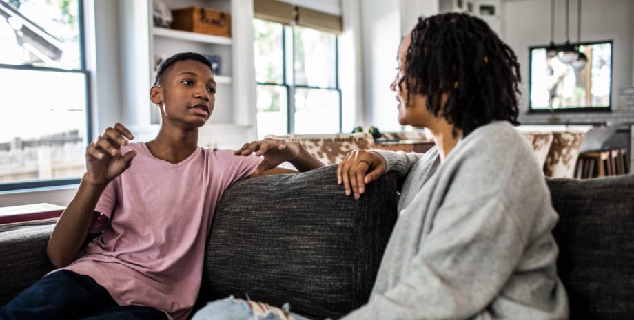 A parent and a child having a discussion on the couch.