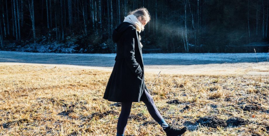 Woman walking alone outside in a heavy coat.