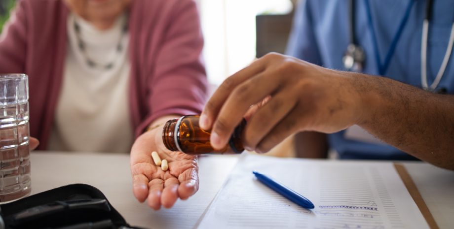 One person handing a pill to another peron