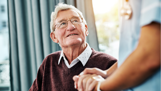 Nurse holding hands with a smiling senior patient