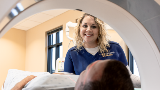 Smiling female nurse practitioner with male patient getting ready for a diagnostic scan
