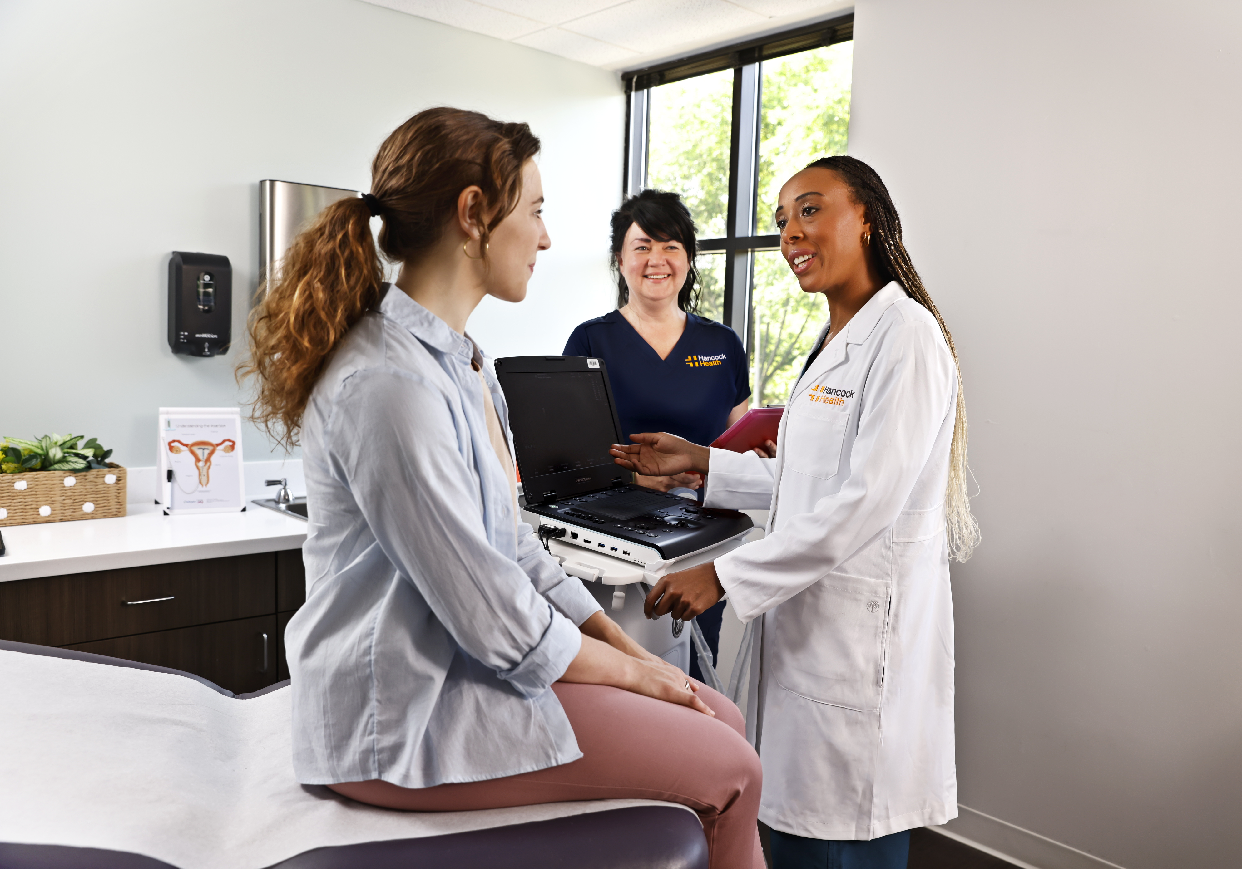 Hancock Health doctor and nurse smiling and talking to patient in an exam room