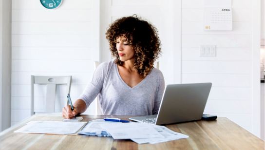 young woman looking at bills and invoices with laptop