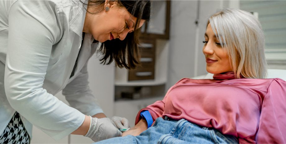 An elderly woman having blood drawn by a doctor.